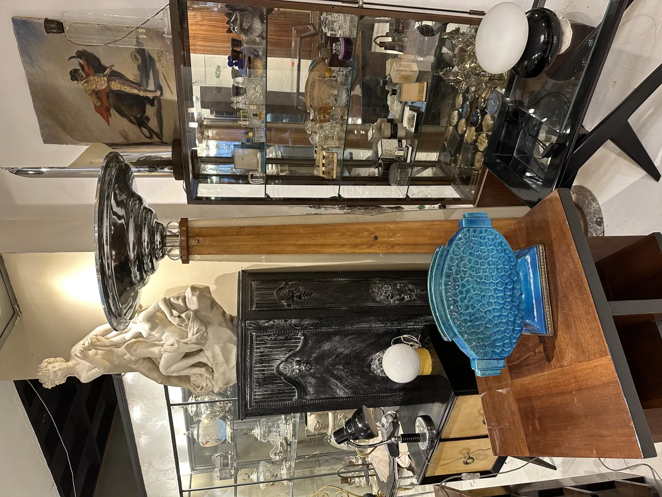 Cerâmica antiga decorativa, azul com design texturizado, com outros objetos ao fundo.