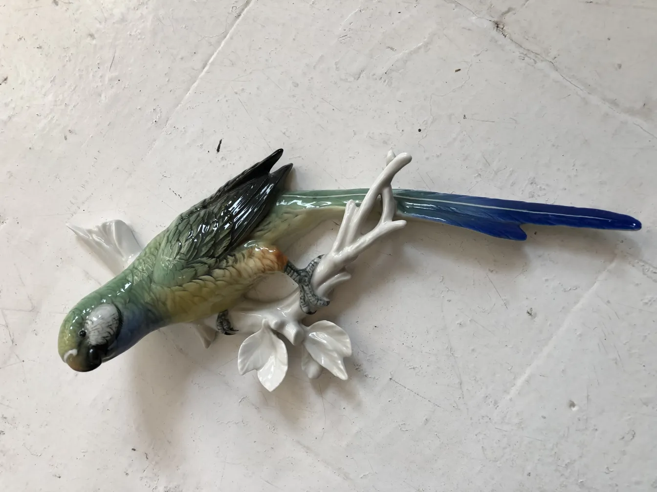 装饰性的古董陶瓷雕塑，展示一只鸟站在白色树枝上。