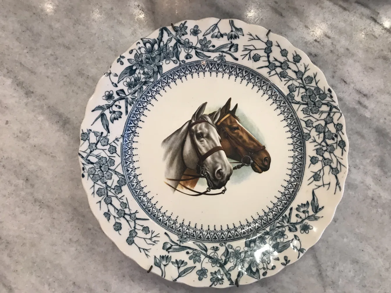 Antiker Keramikteller mit Pferden und Blumenmuster.