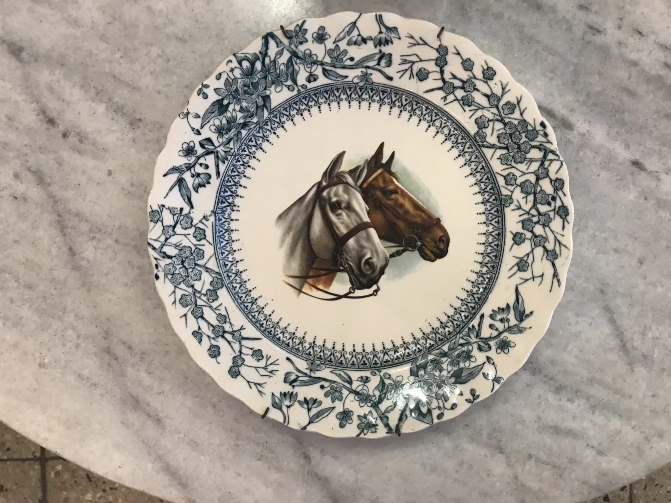 Platillo antiguo con ilustraciones de caballos y flores azules