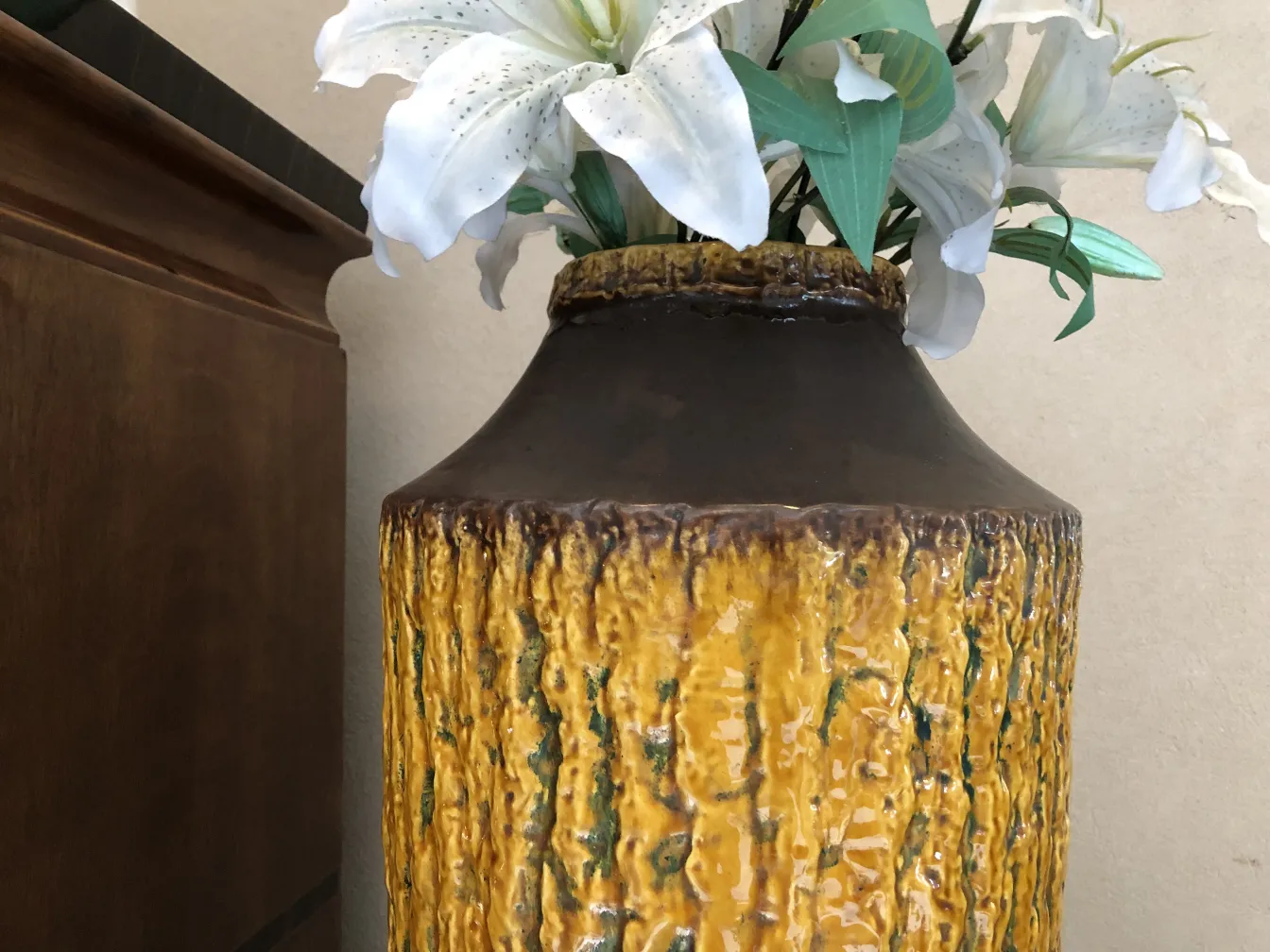 Vase en céramique ancienne avec des fleurs blanches et une texture jaune.