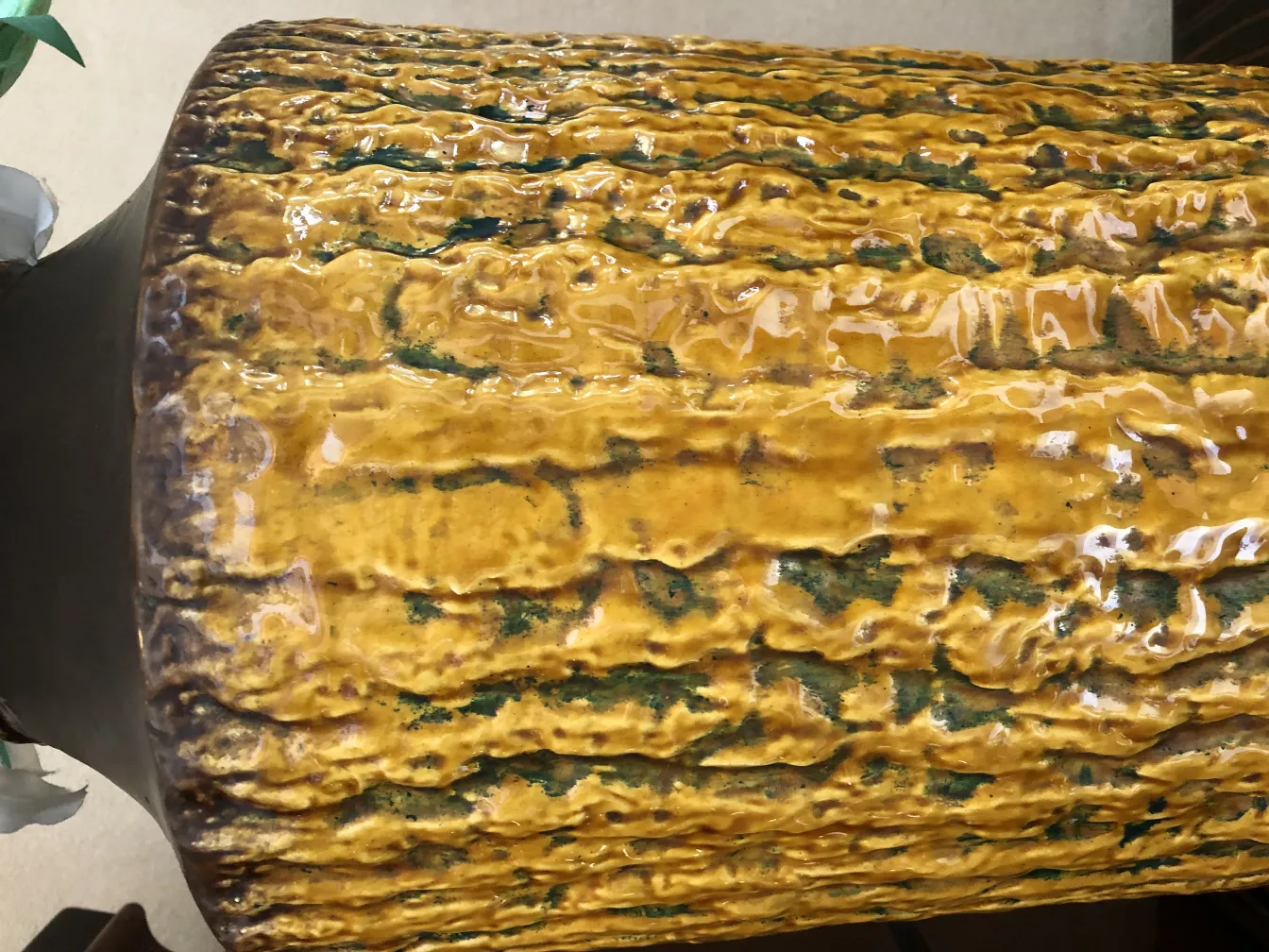 Céramique ancienne avec texture jaune et verte, décoration rustique.