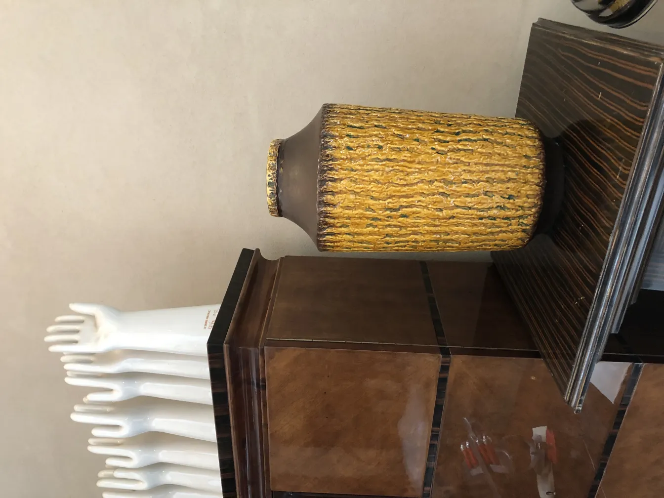 Vaso de cerâmica antiga com textura dourada, em um ambiente elegante.