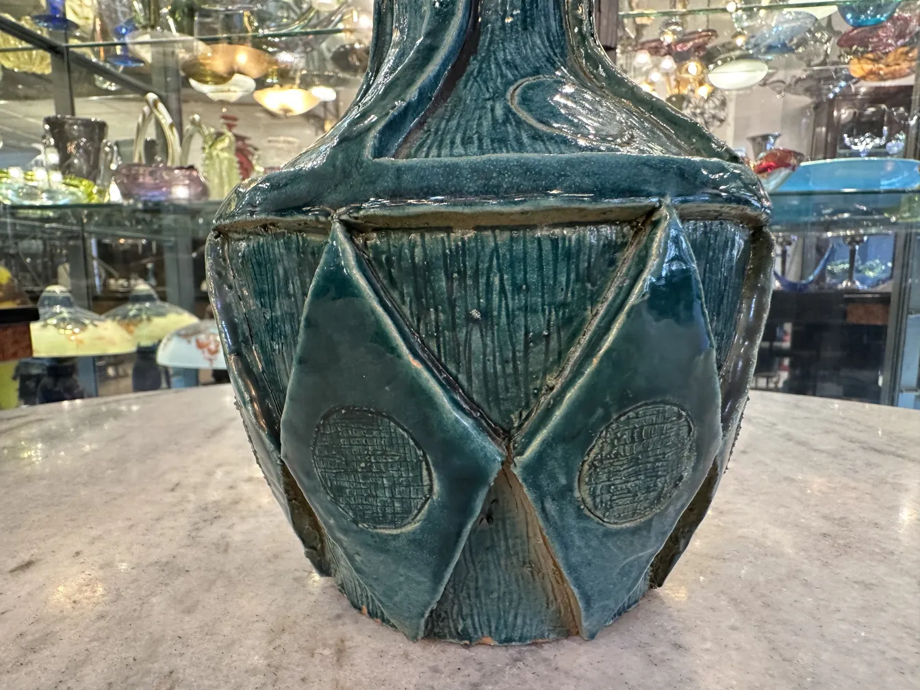 Antiker Keramikvase mit eingeprägtem Design und glänzender Oberfläche, umgeben von Antiquitäten.