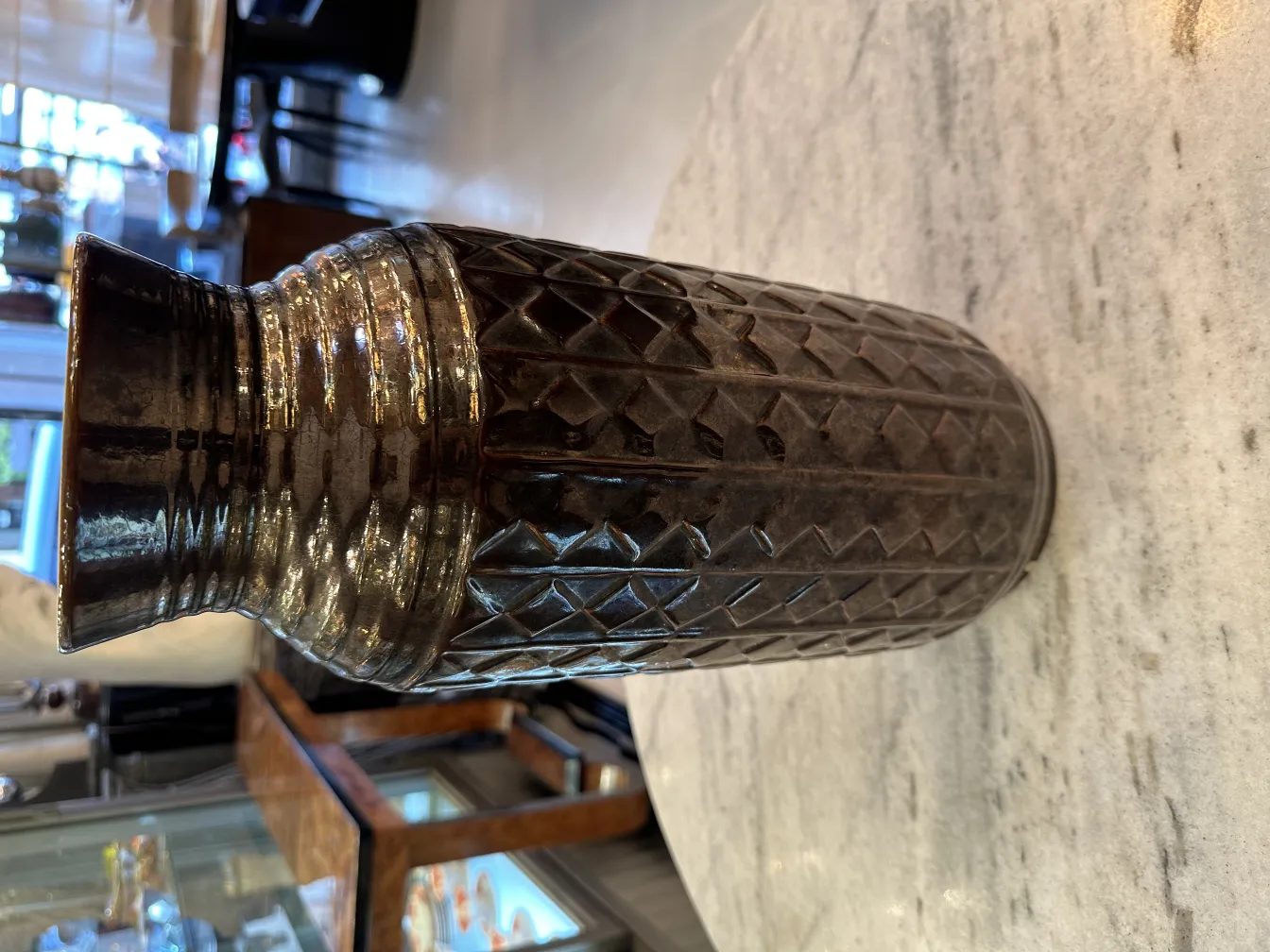 Antique ceramic vase with intricate designs and sheen, displayed in an elegant setting.