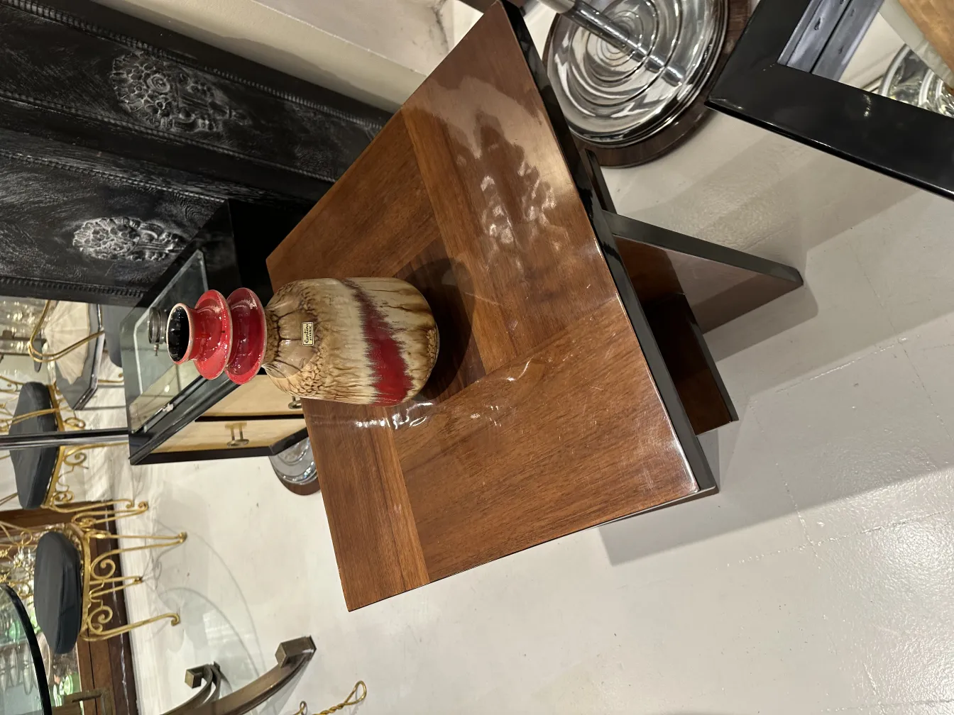 Cerâmica decorativa antiga com tons vermelhos e beges sobre uma mesa de madeira