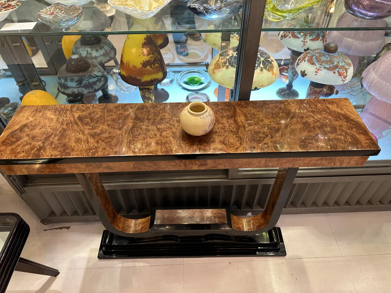 Piccolo contenitore in ceramica antica di colore chiaro, decorato, su un tavolo di legno lucido.