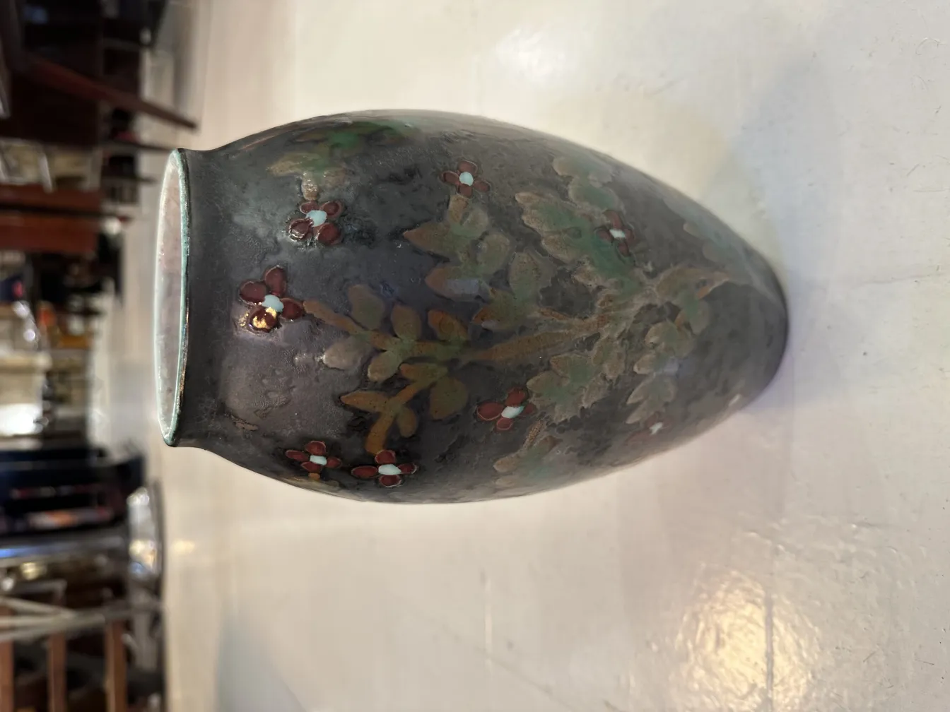 Antique ceramic vase with colorful floral design, light background.