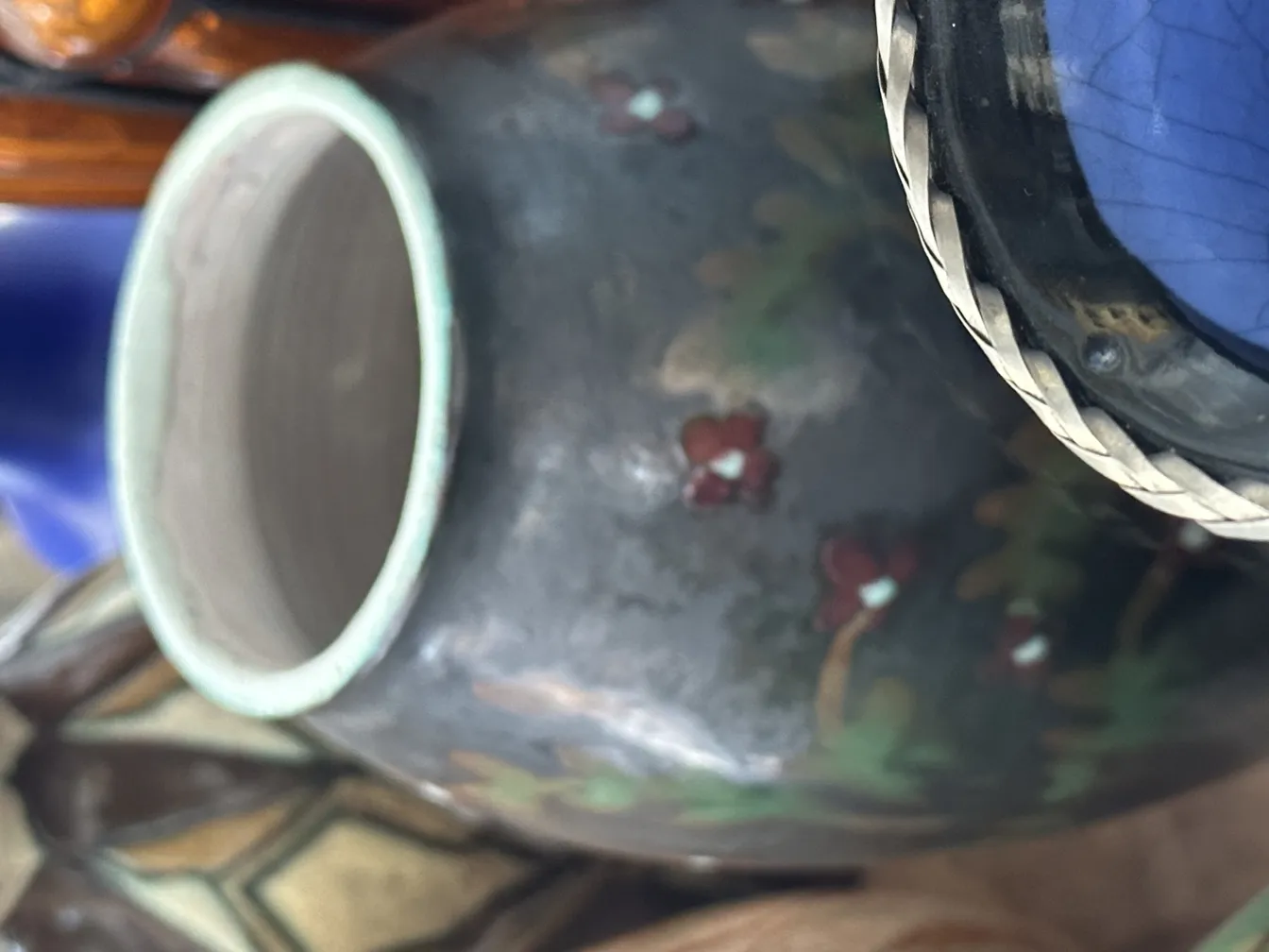 Vaso di ceramica antica con fiori rossi dipinti su sfondo scuro.