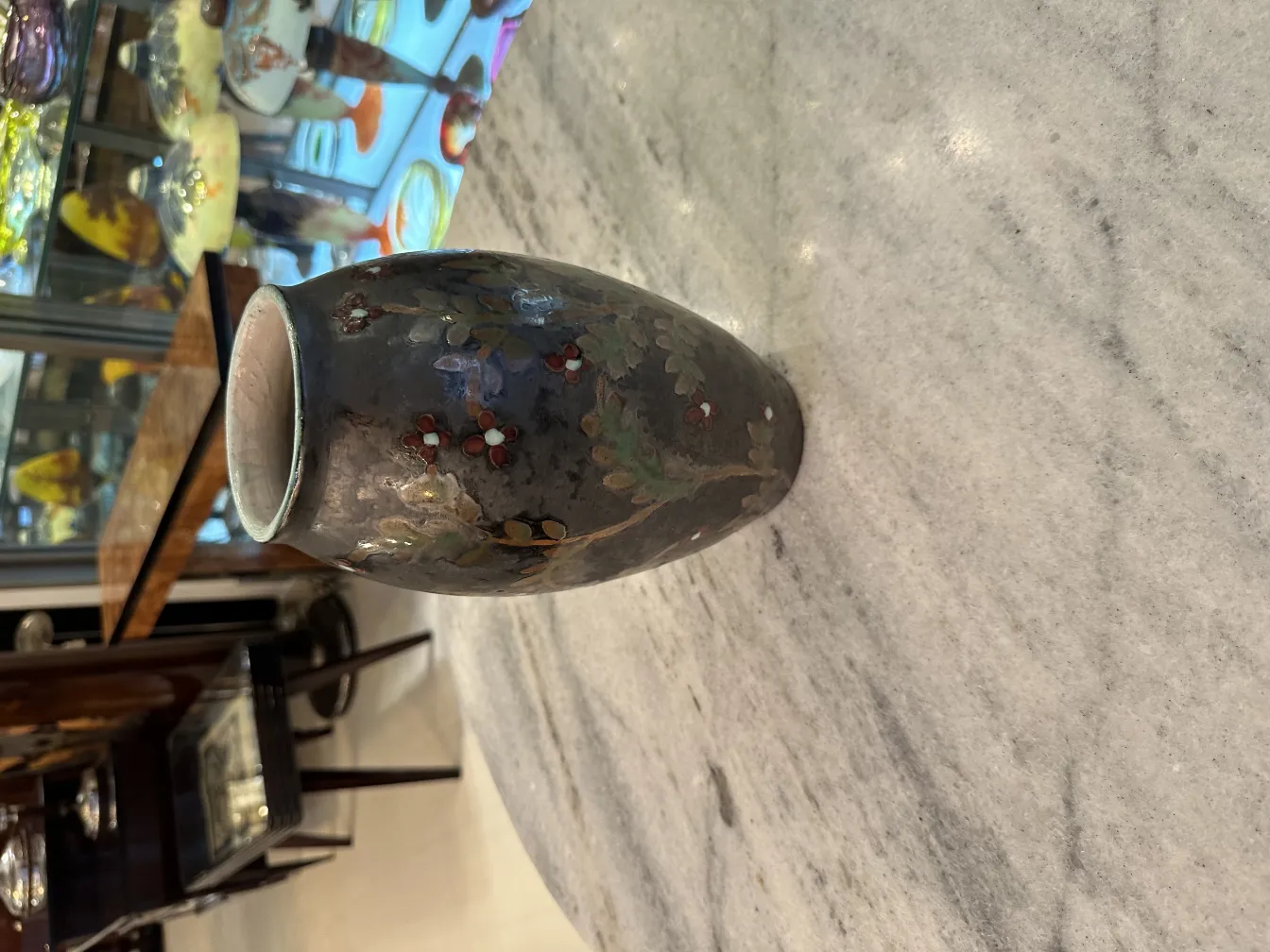 Jarrón de cerámica antigua con detalles florales coloridos.