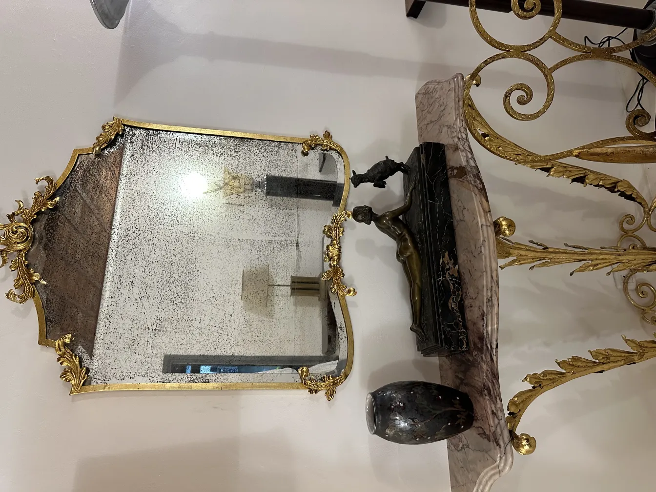 装飾的な古代陶器が金色の鏡のそばにあります。