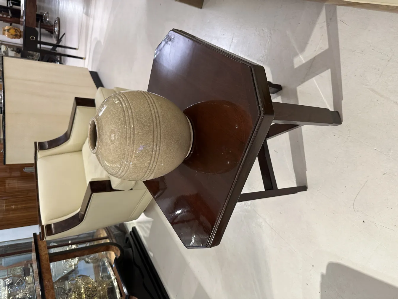 Antique ceramic jar on a wooden table with chairs in background