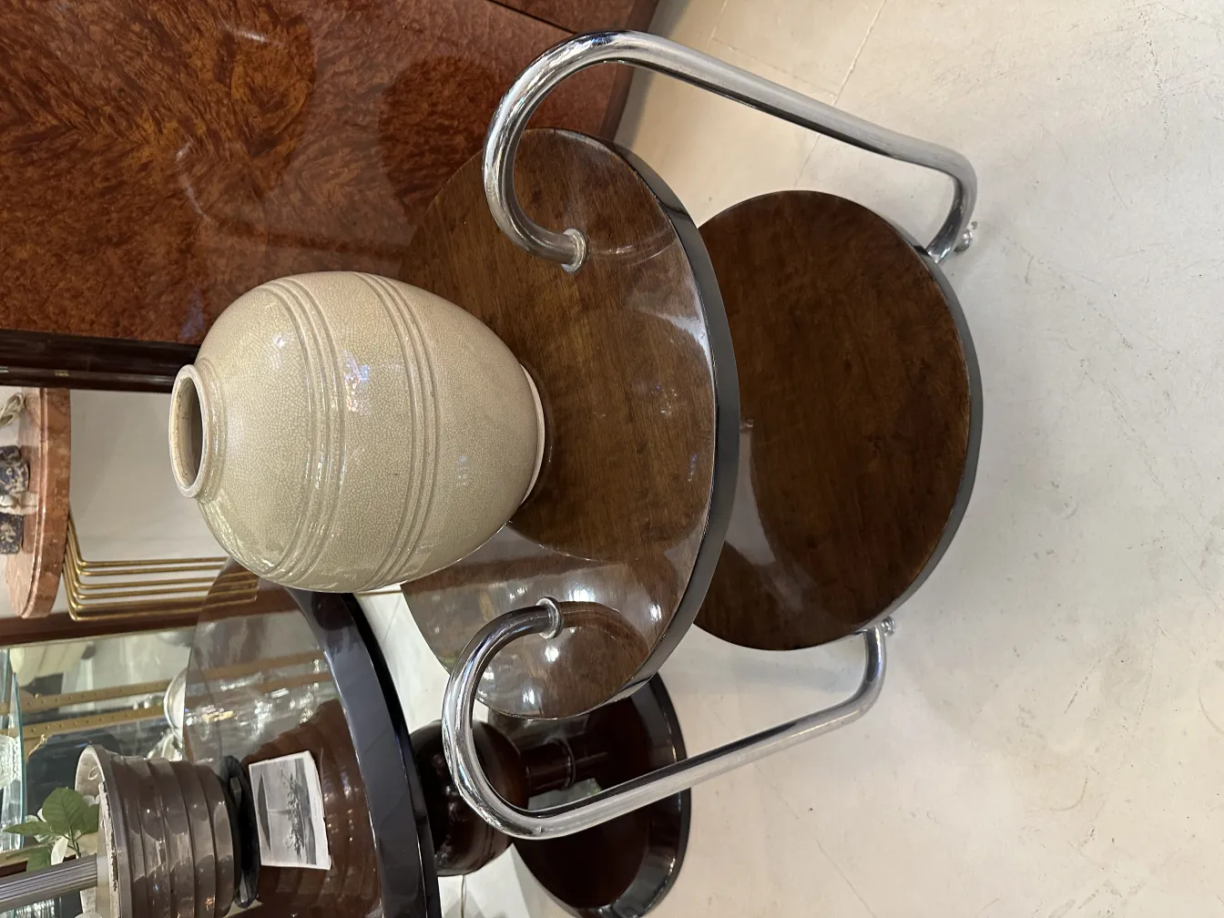 Jarrón antiguo de cerámica con diseño decorativo en tonos claros, sobre mesa de madera.