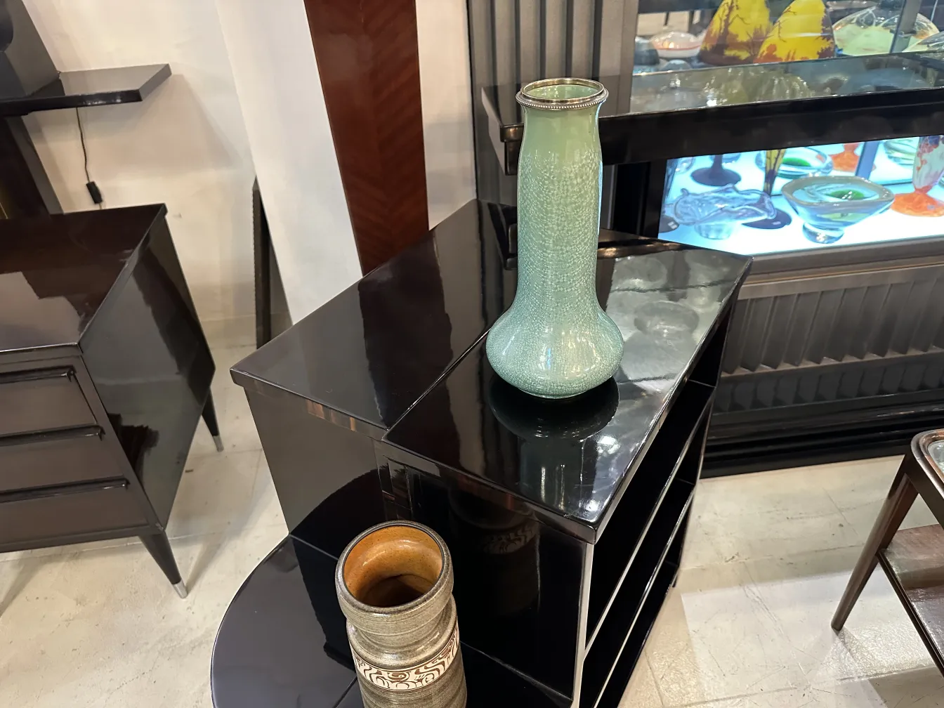Vaso de cerâmica antiga em um móvel preto brilhante.