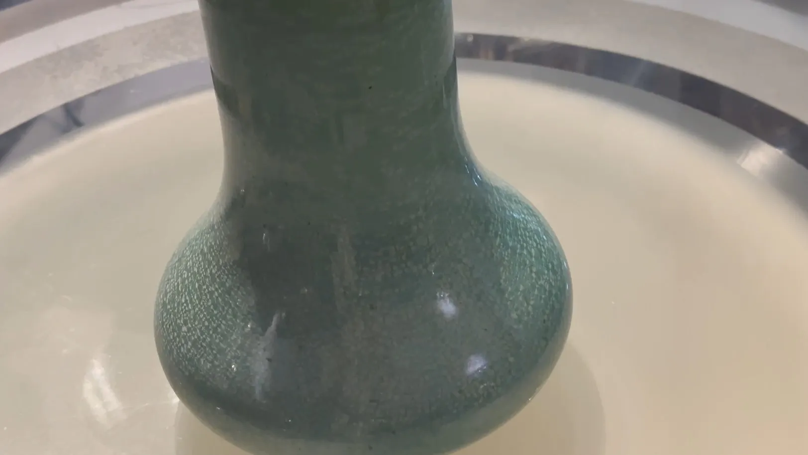 Vaso de cerâmica antiga com acabamento verde brilhante e textura.