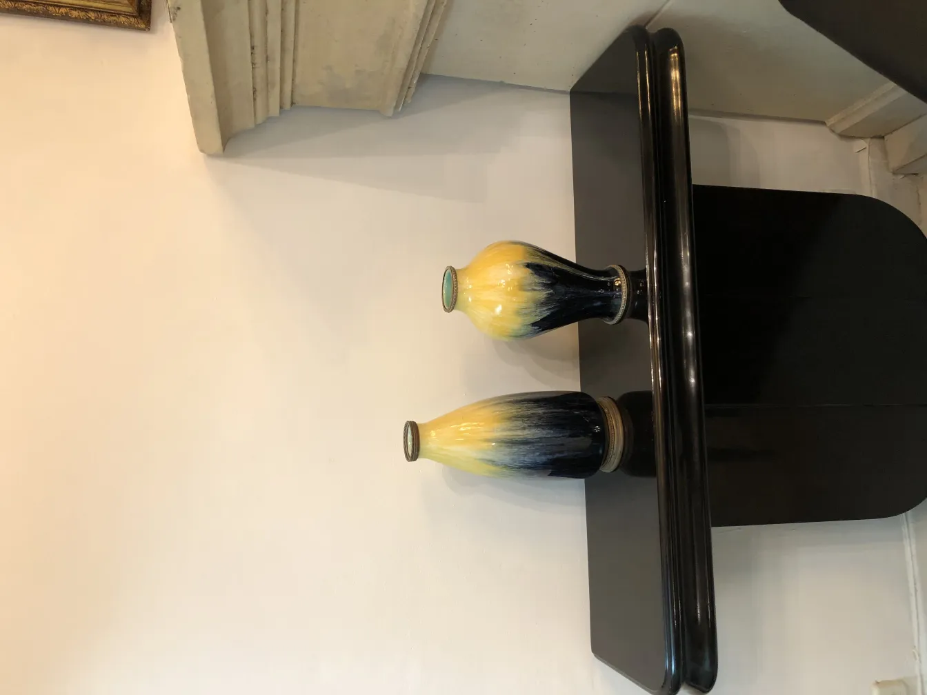 Two antique ceramic vases on a black table, yellow and black.