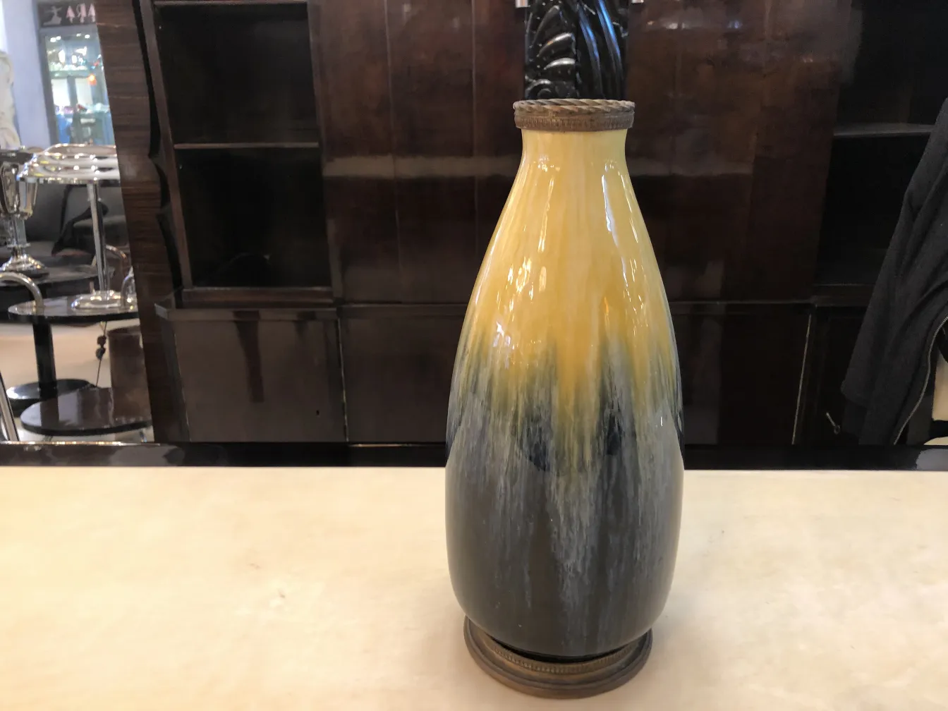 Vaso antigo de cerâmica amarelo e preto em um ambiente elegante.