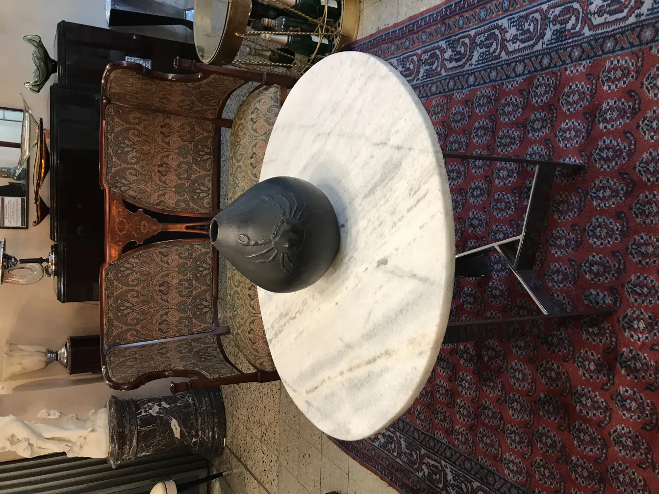 Antike schwarze Keramikvase auf einem weißen Tisch.