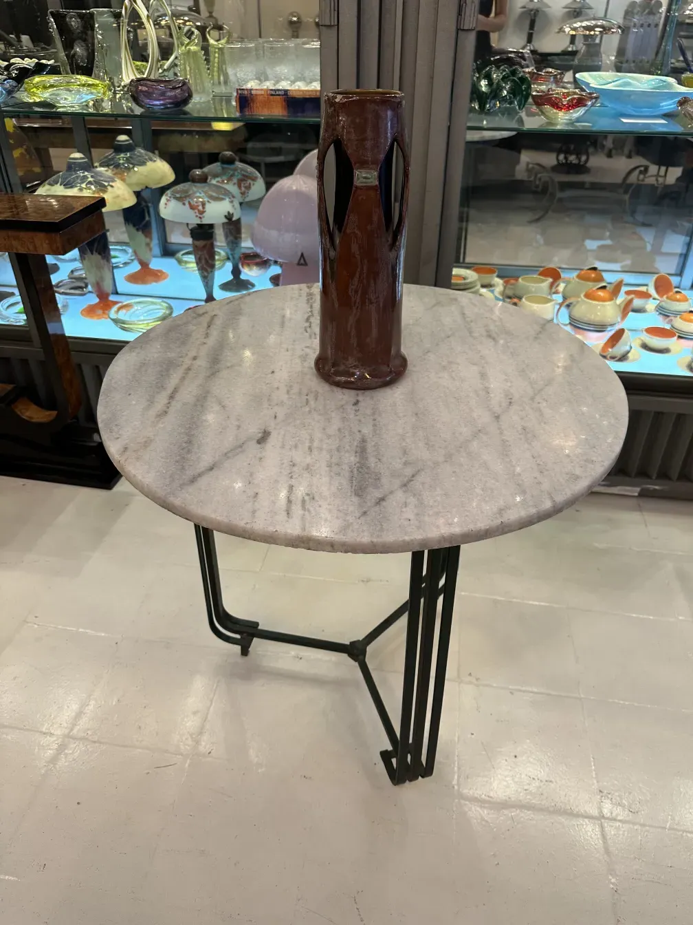 Brauner Keramikvase auf rundem Tisch in antikem Umfeld.