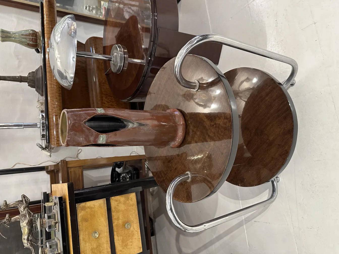 Vasija antigua de cerámica con diseño excentrico, en un entorno de muebles retro.