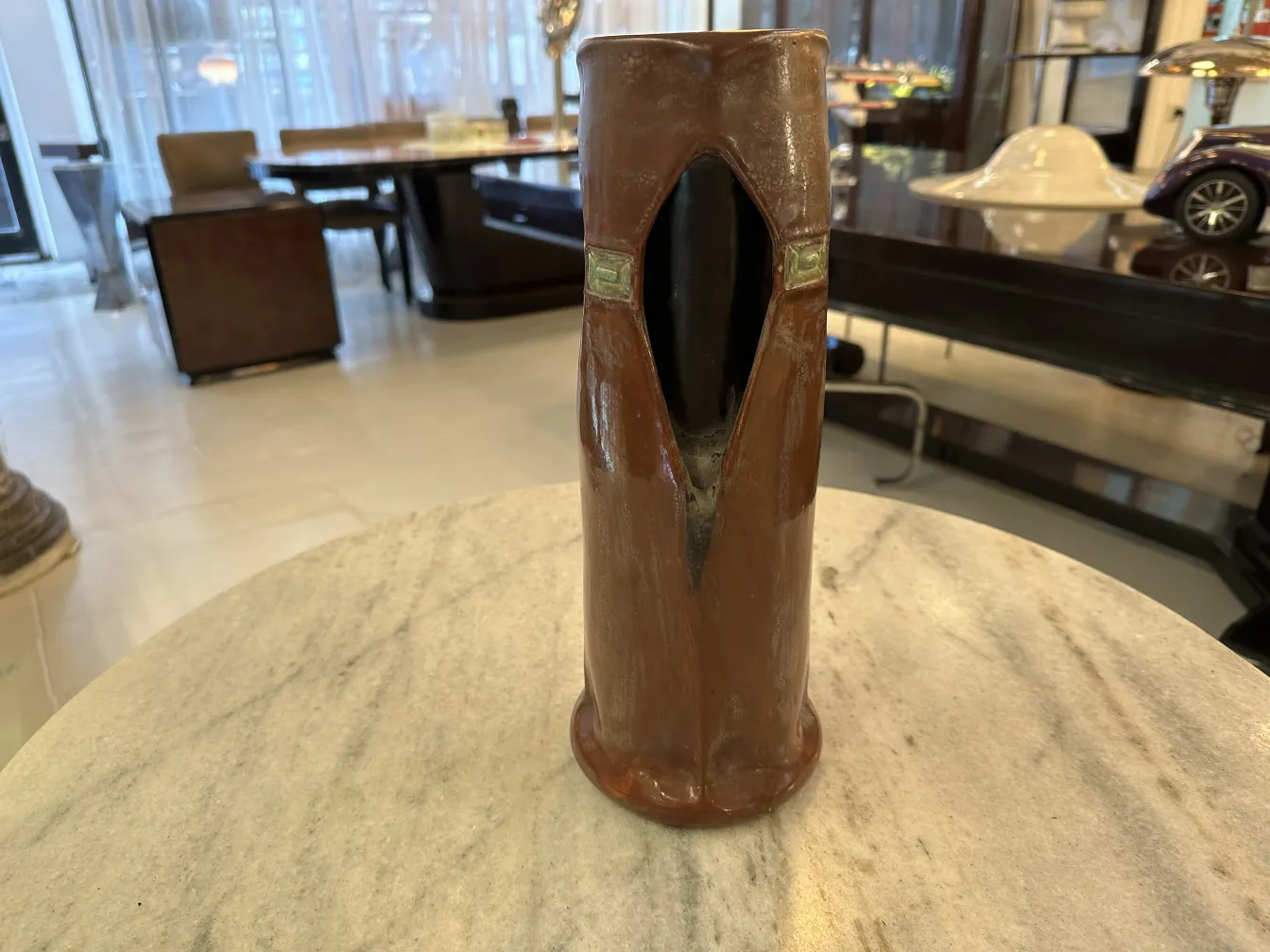 Antique ceramic shaped like a coat, shiny brown. Elegant setting.