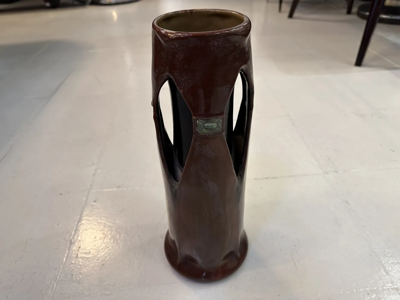 Vaso antico in ceramica decorativa di tonalità marroni con forma elegante, su una superficie chiara