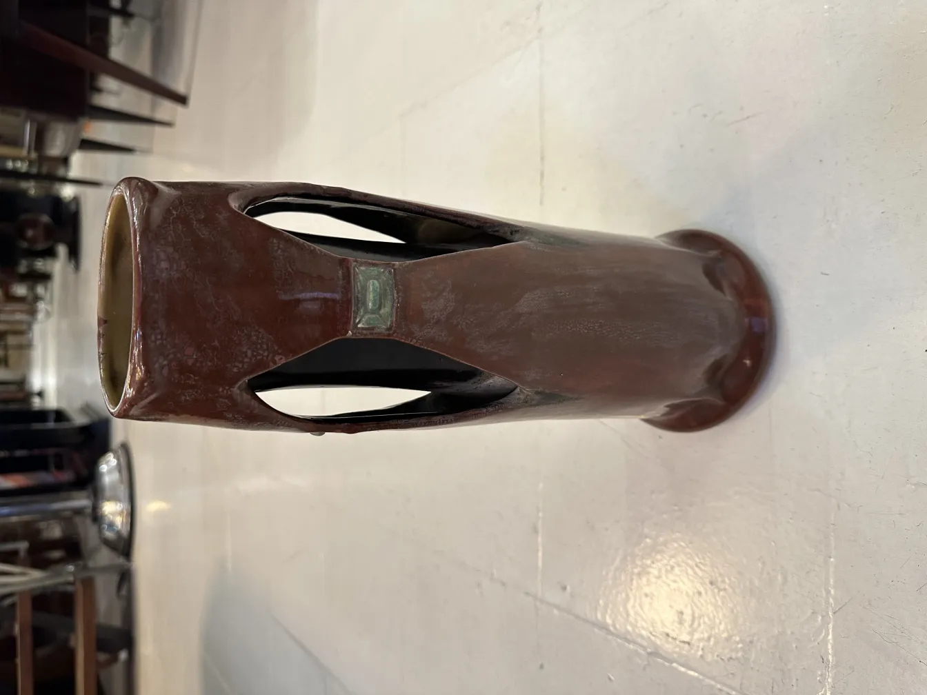 Vase antigo de cerâmica com cortes decorativos, ambiente elegante.