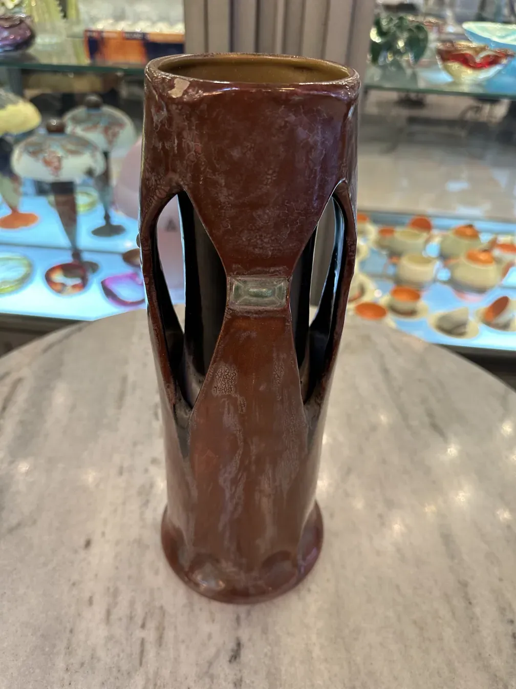 Vaso cerâmico antigo com design curvo distinto em tons marrons, ambiente decorativo.