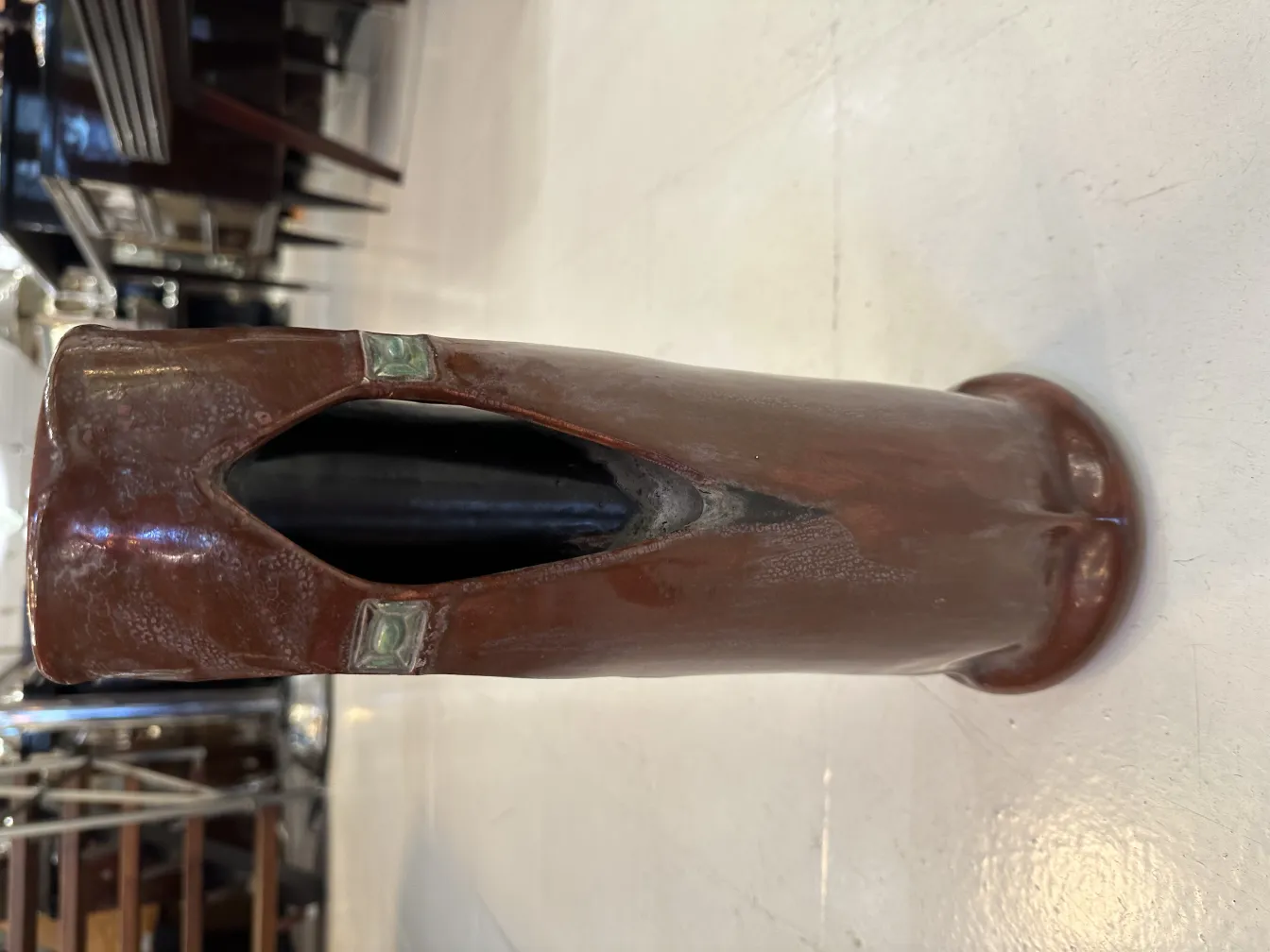 Antique ceramic vase with ornate details and dark brown color.