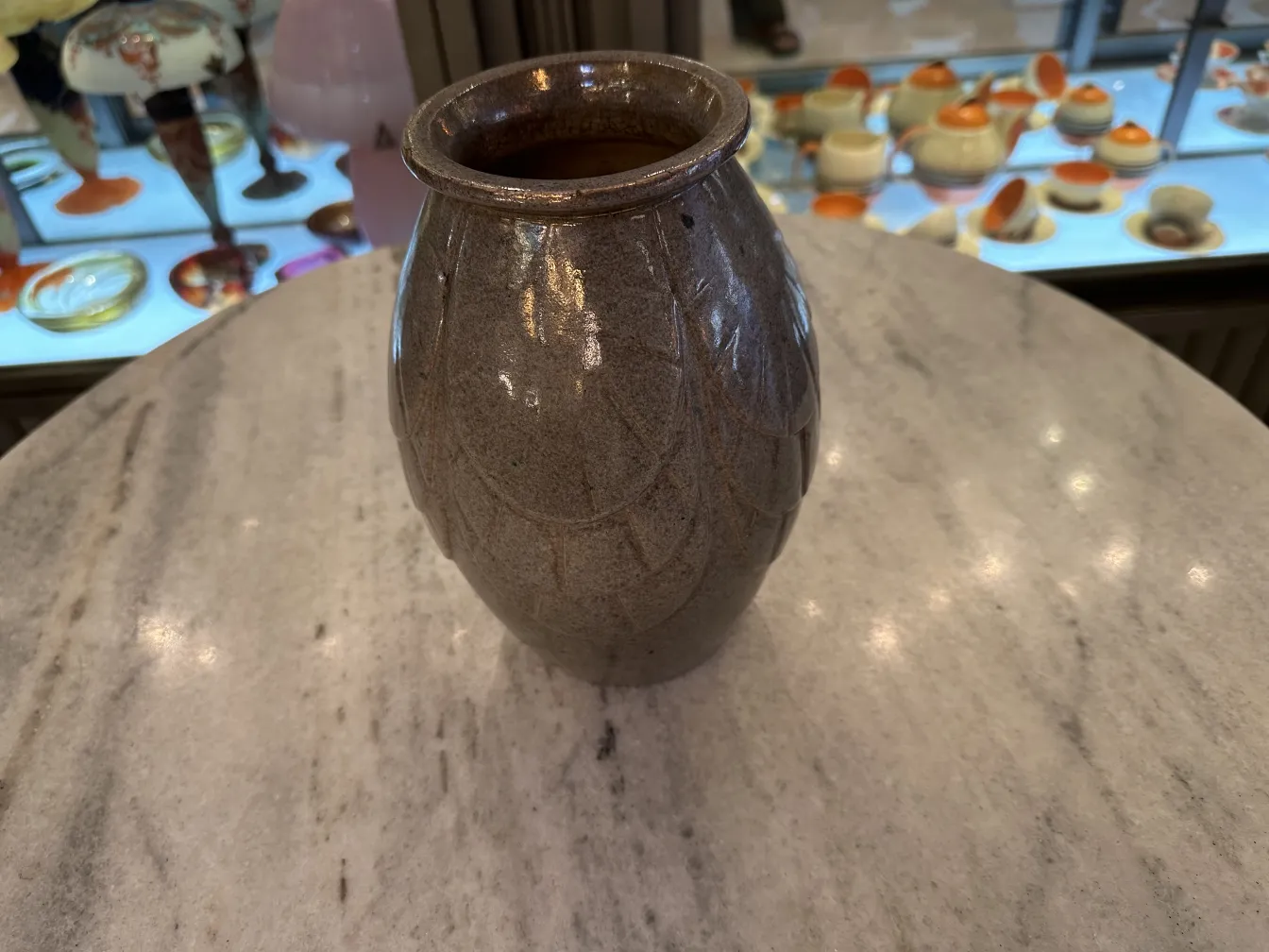 Vase en céramique ancienne avec décoration texturée, dans un cadre élégant.