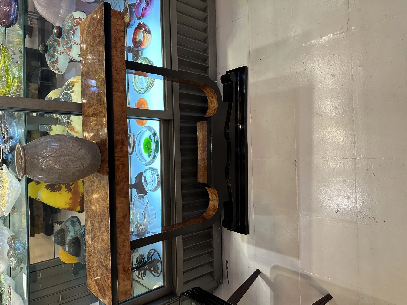 Jarrón de cerámica antiguo expuesto en vitrina con otros objetos decorativos coloridos