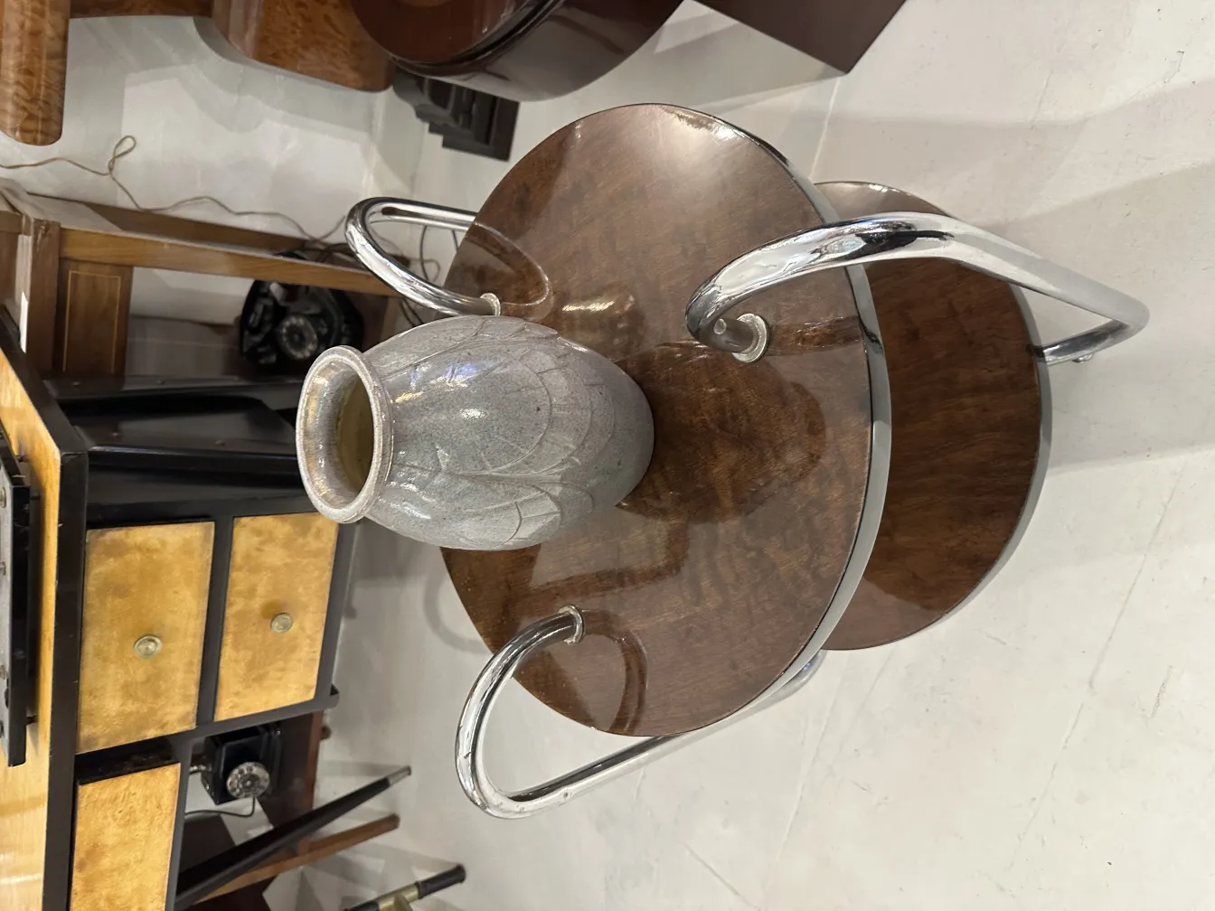 Vase en céramique ancienne avec finition grise et motif sur une table en bois.