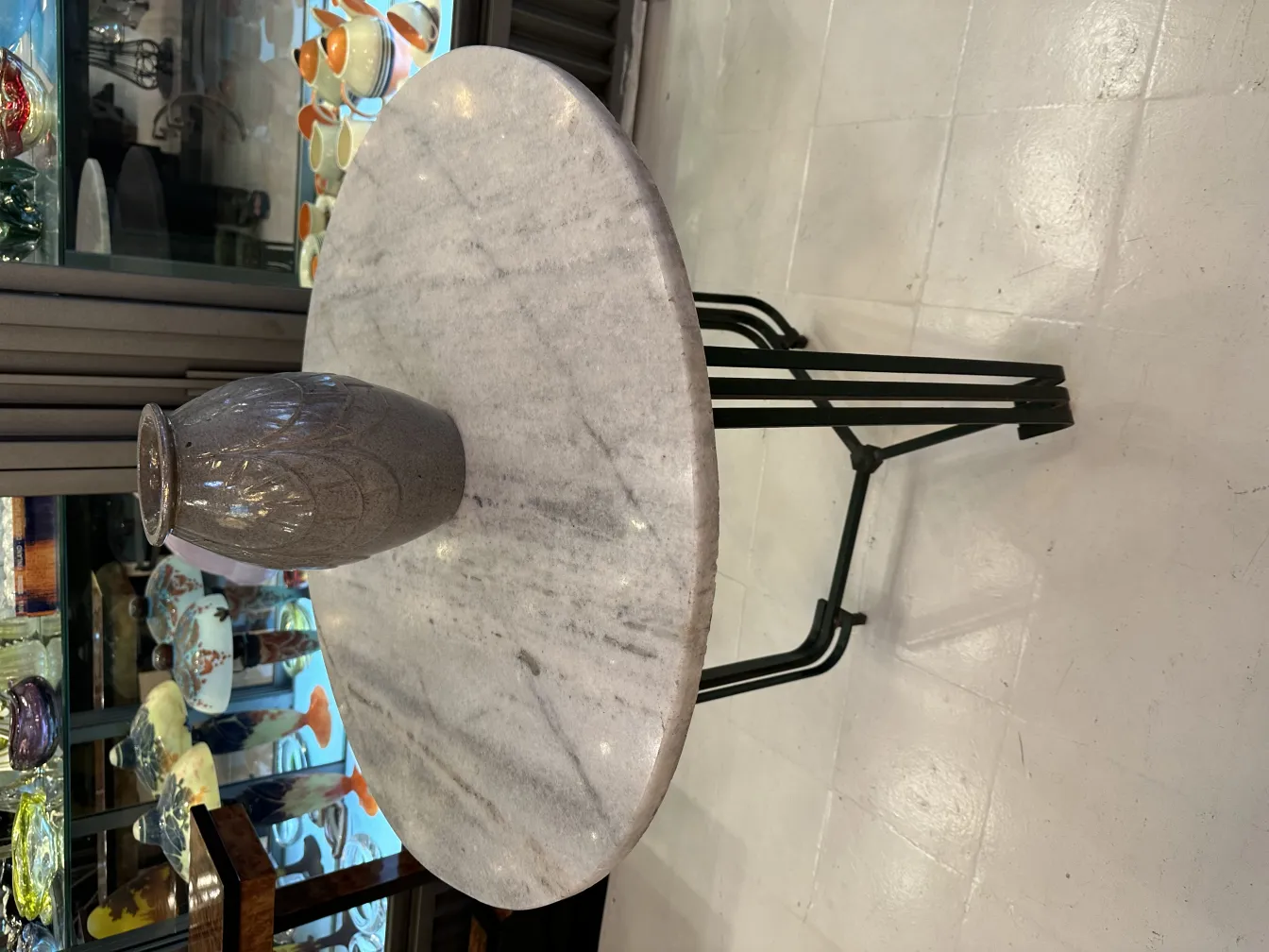 Jarrón antiguo de cerámica decorativa sobre una mesa moderna, con fondo de antigüedades.