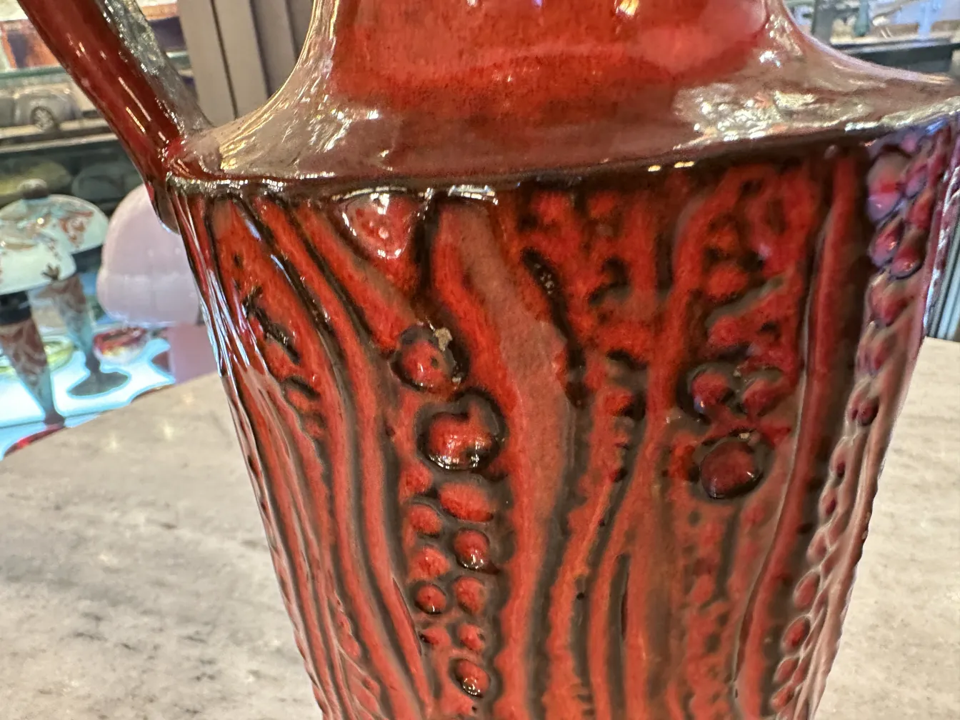 Vase ancien en céramique avec surface texturée rouge et noire.