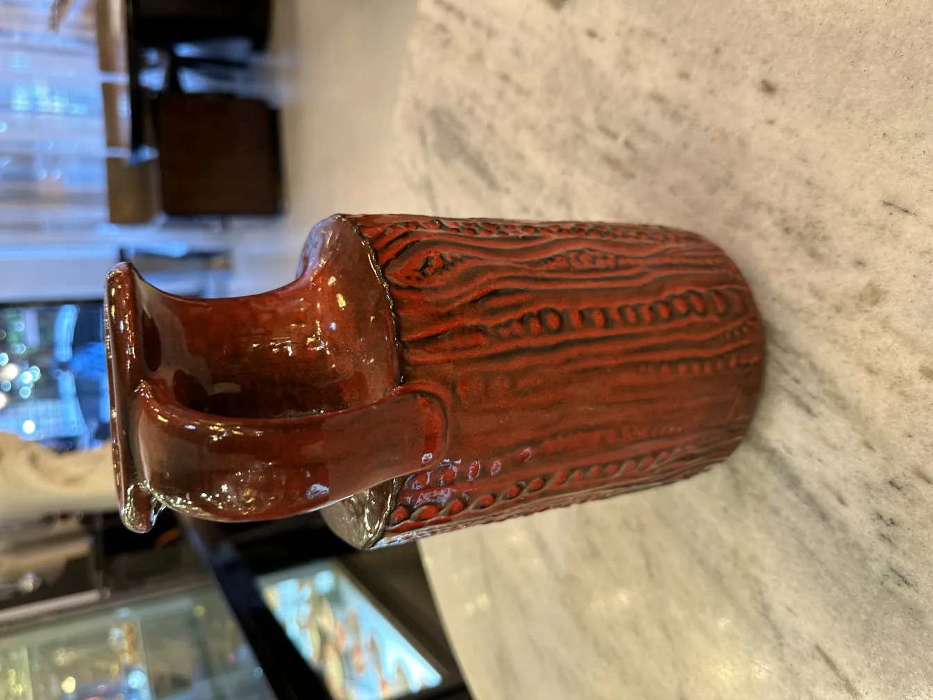 Antique ceramic vase with carved design in brown tones.