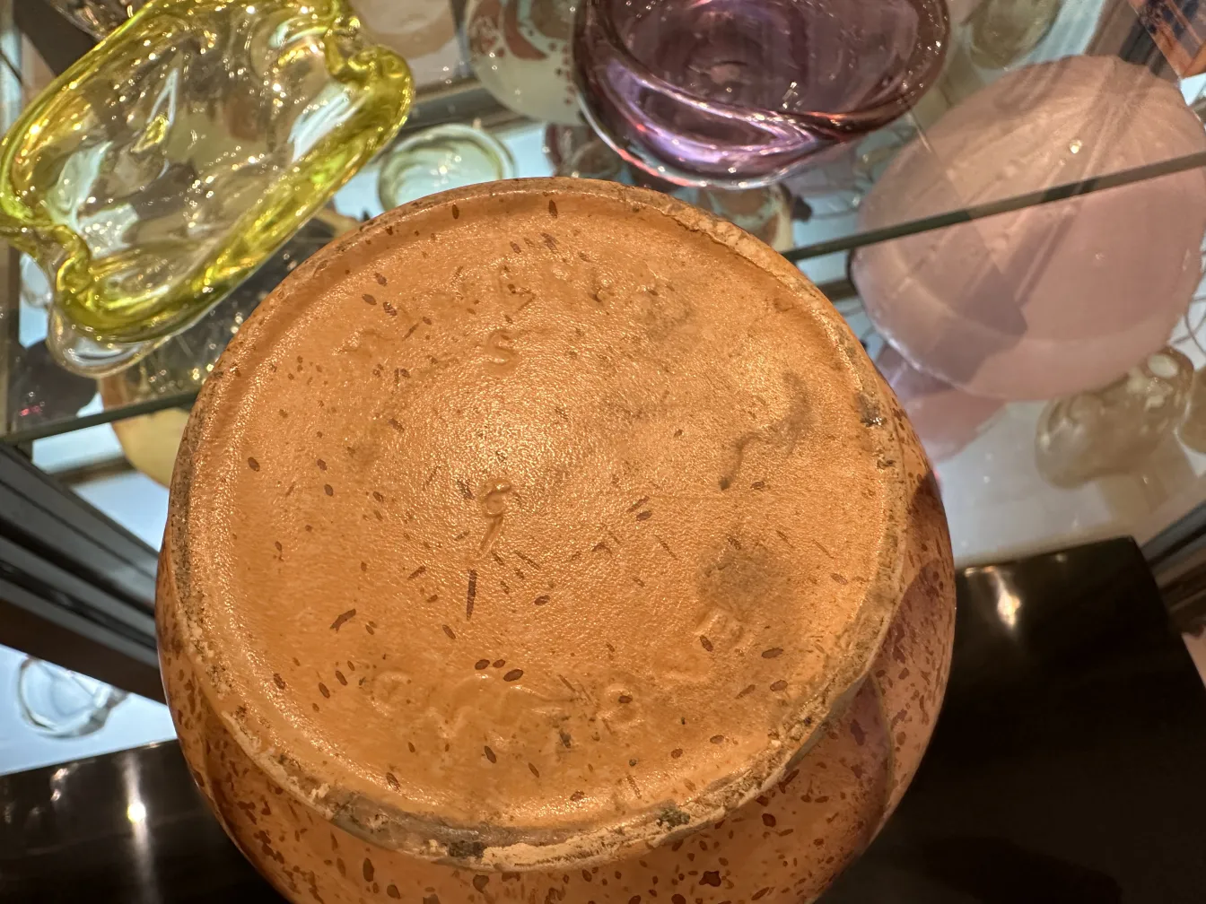 古董陶器底座，带有独特细节。背景为其他装饰物品。