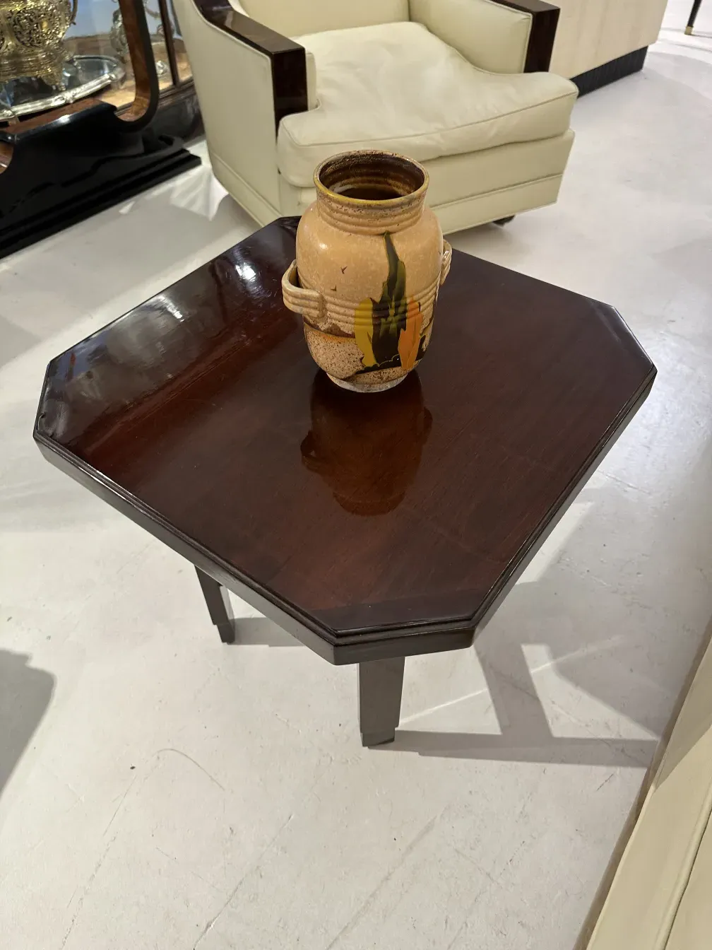 Vaso in ceramica antica su un tavolo ottagonale in un ambiente elegante.