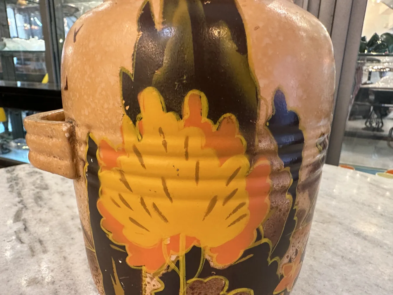 Antiker Keramikkrug, dekoriert mit gelben und orangefarbenen Blumen.