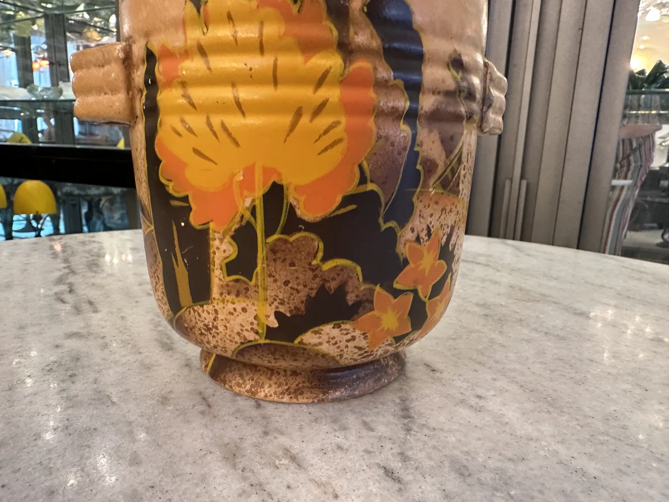 Vaso in ceramica antica con decorazione floreale colorata su sfondo scuro.