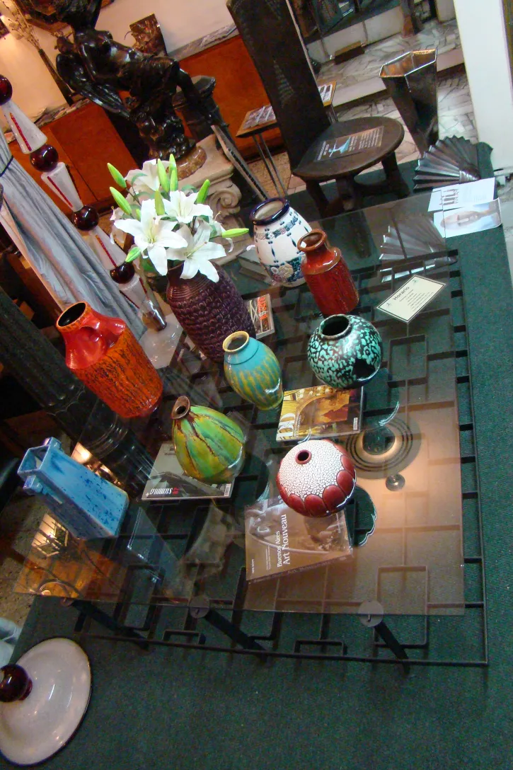 Collection of colorful antique ceramics on a glass table.