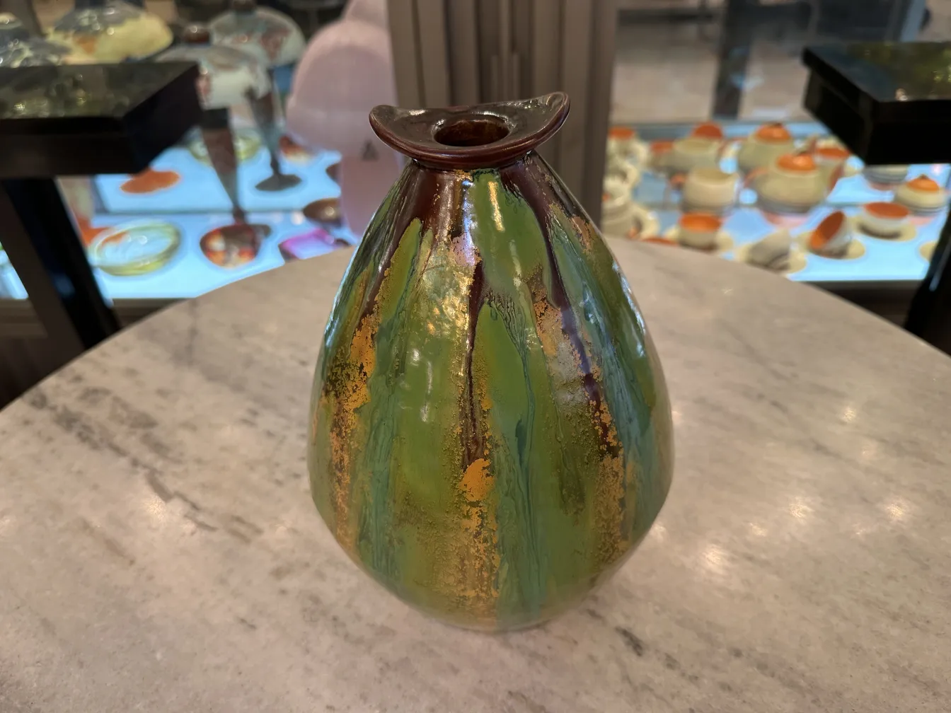 Vaso colorido de cerámica antiga com tons verdes e dourados.