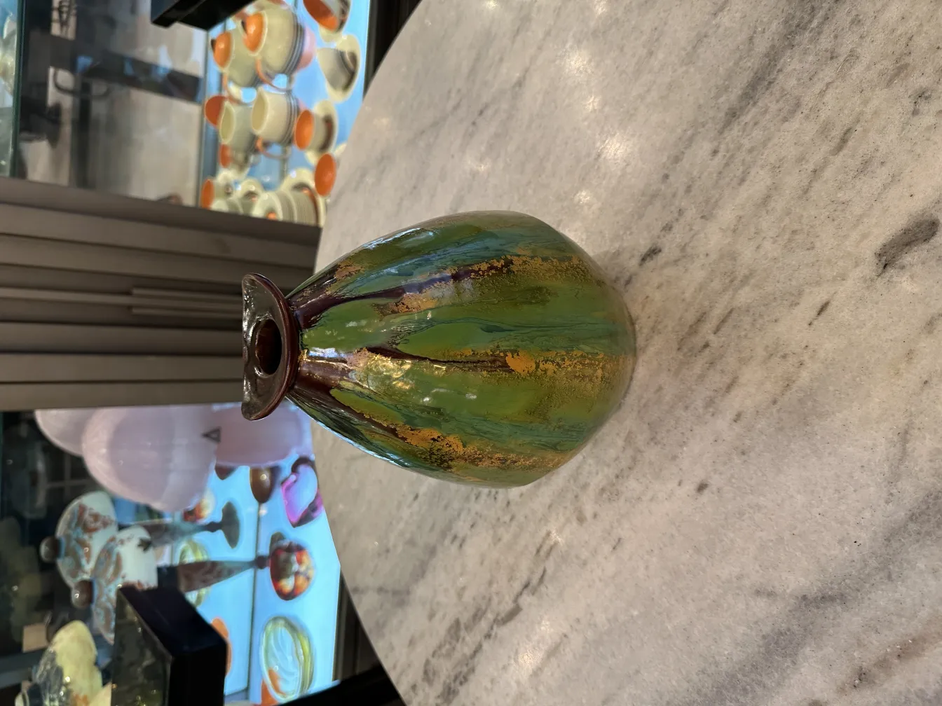 Antique ceramic vase in green and gold, decorative background.