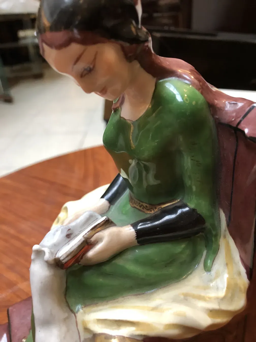 Figura di ceramica antica di una donna che legge in un ambiente accogliente.