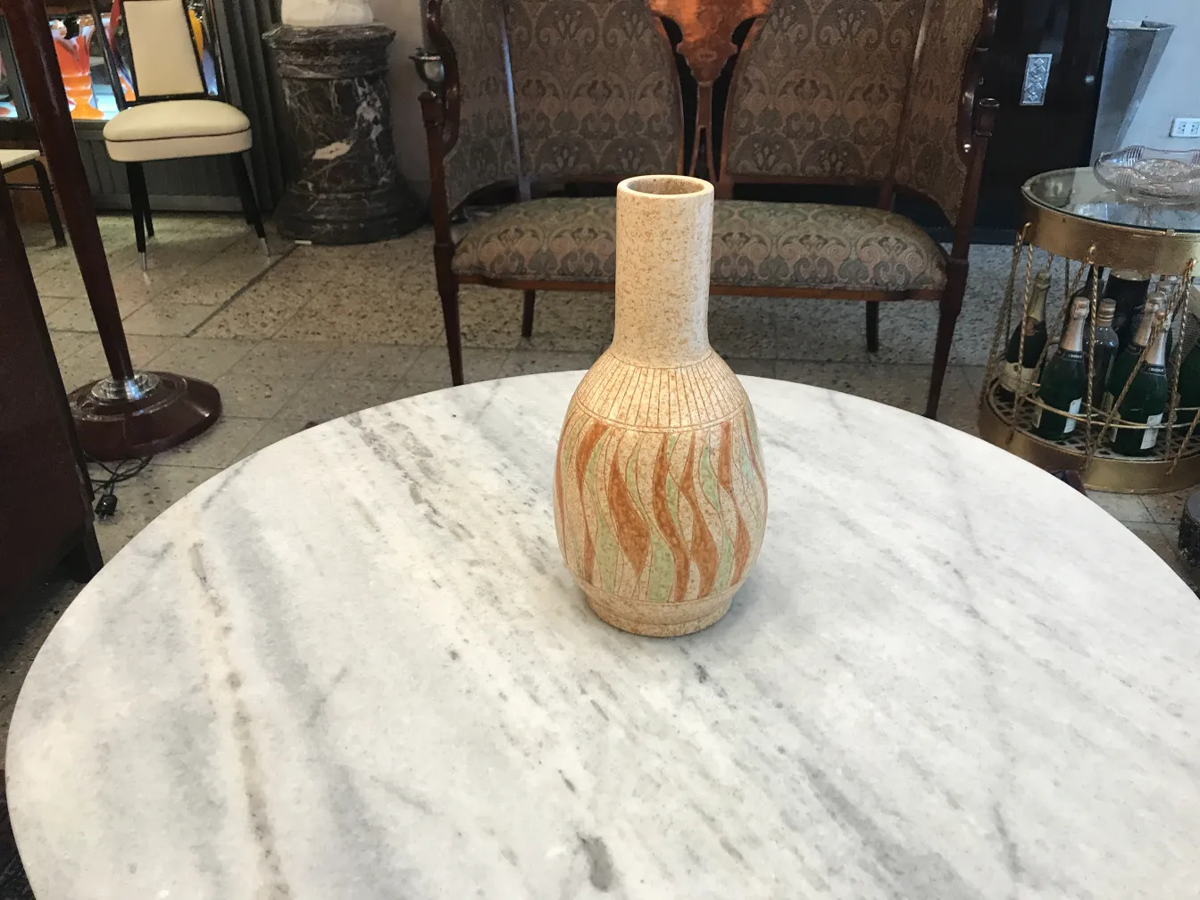 vase in ceramica antica con design in tonalità calde su tavolo di marmo