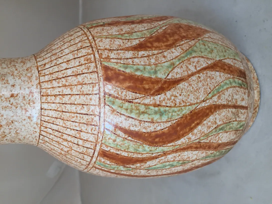 Vase en céramique ancienne avec des motifs ondulés dans des tons bruns et verts.
