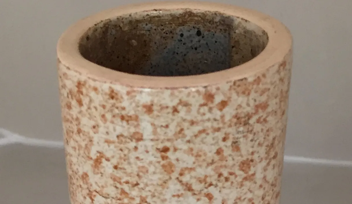 Vaso di ceramica antica con texture irregolare e tonalità naturali.