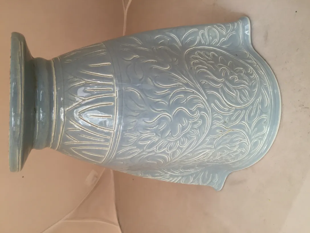 Antiker Keramikvase in Blau mit Reliefmustern vor einem neutralen Hintergrund.