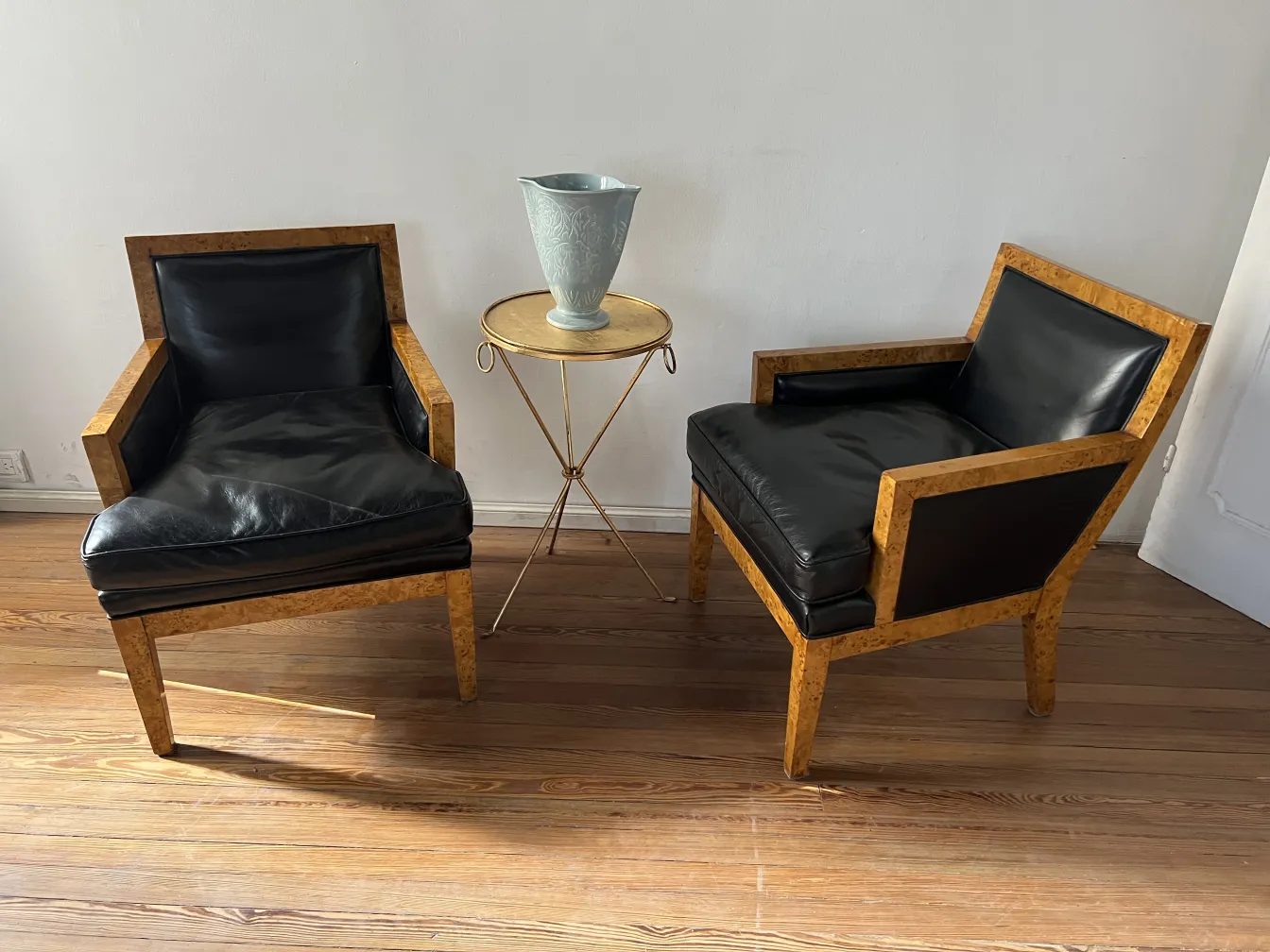 Antiga cerâmica decorativa sobre uma mesa dourada ao lado de poltronas.