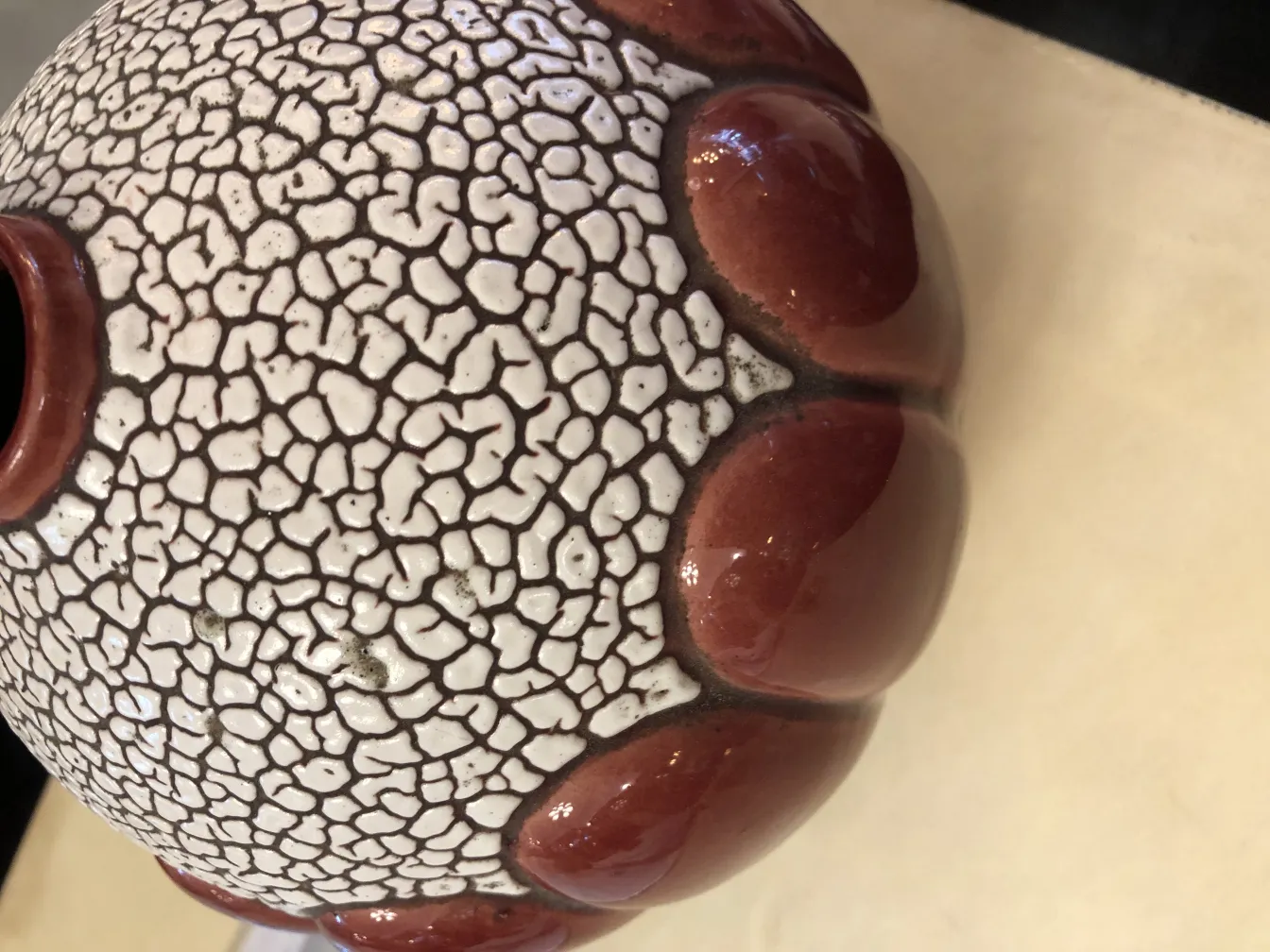 Антикварная керамическая ваза с треснутой поверхностью и красными деталями.