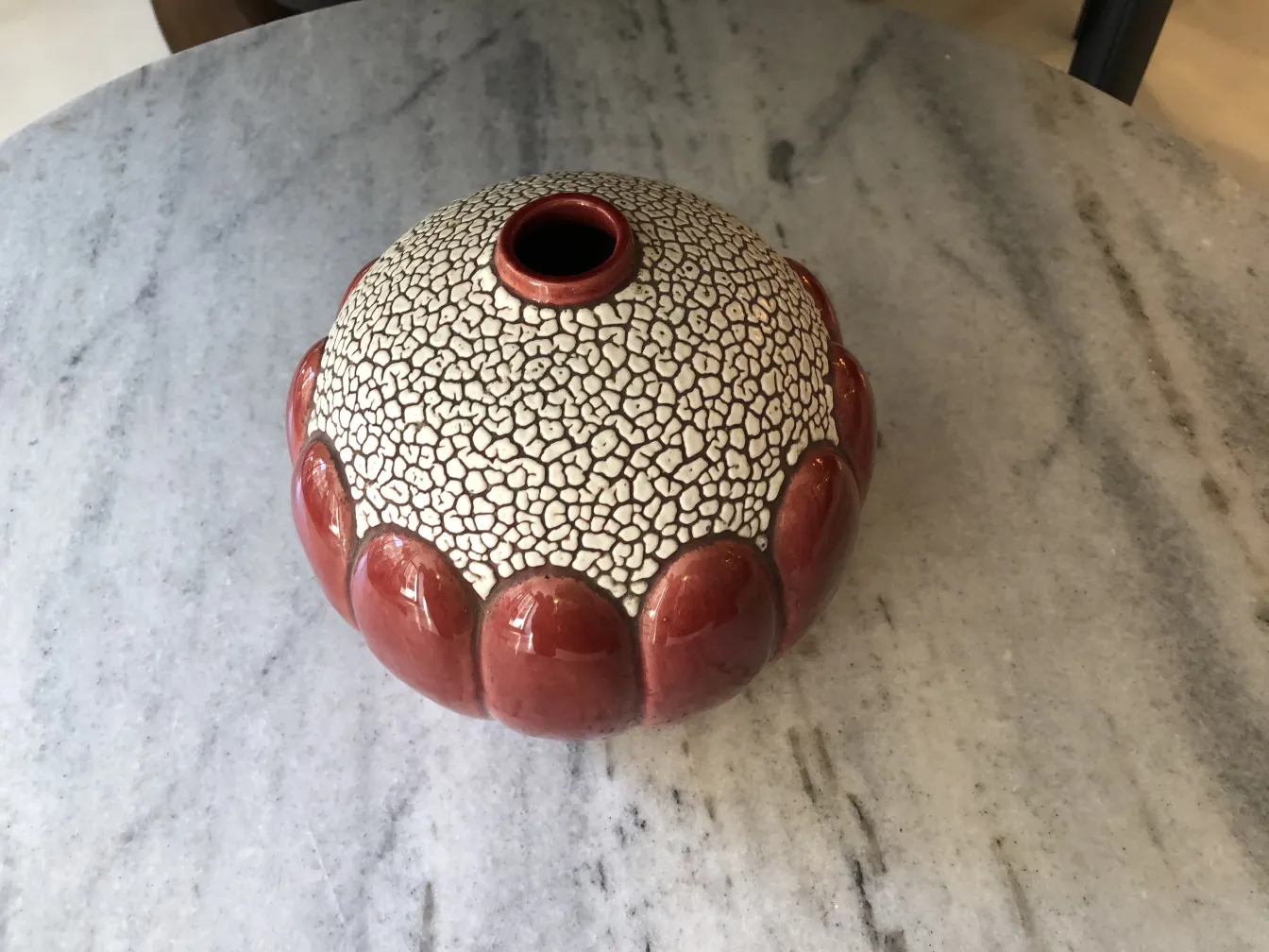 Vase en céramique ancienne avec texture craquelée et base rouge.